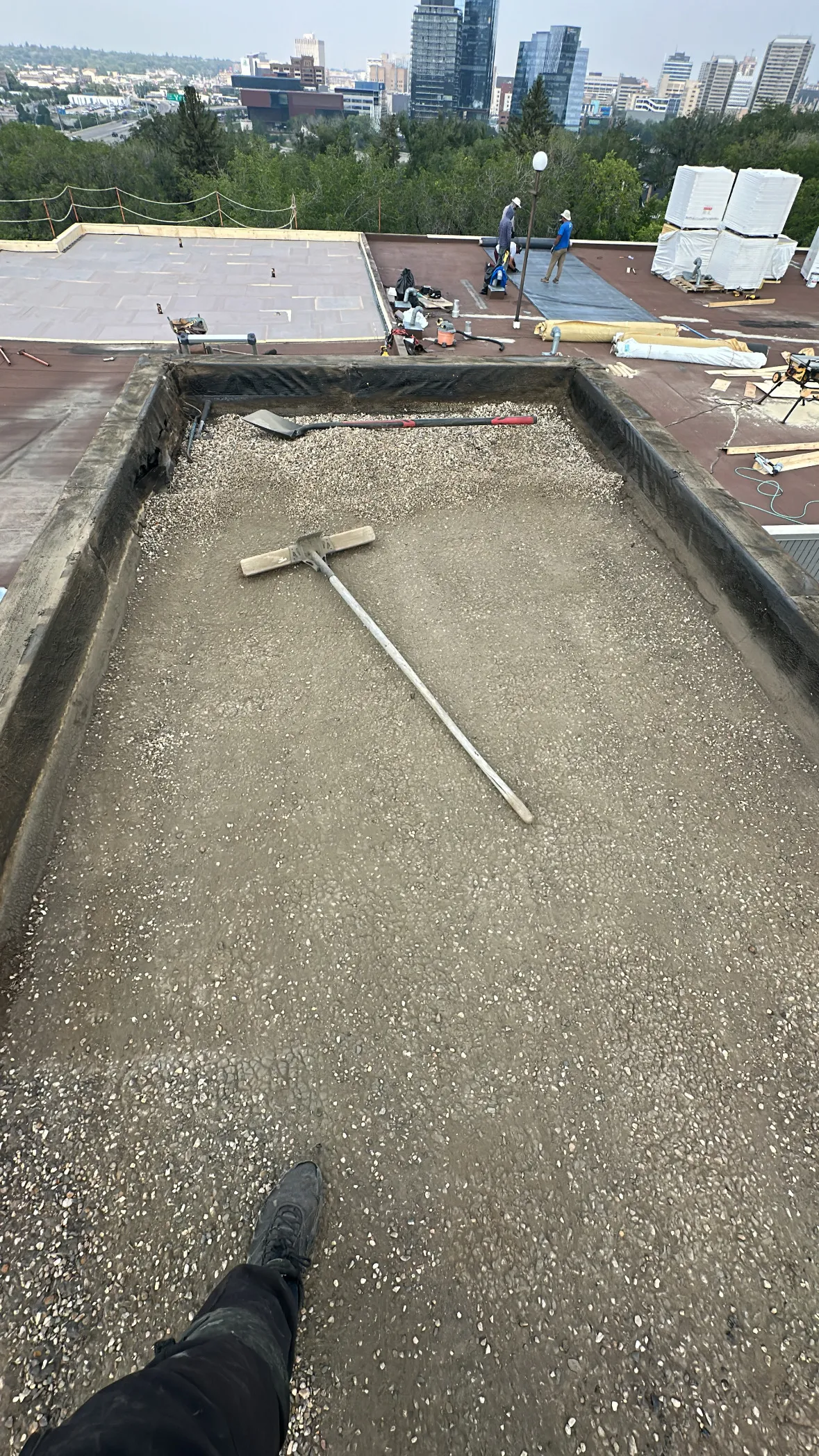 Downtown Calgary skyline behind a commercial flat roof tear-off with gravel