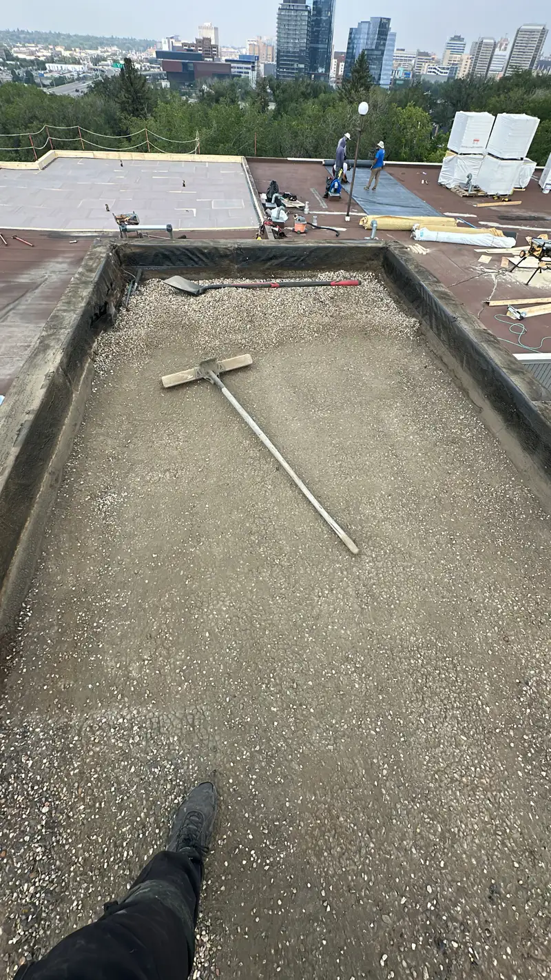Downtown Calgary skyline behind a commercial flat roof tear-off with gravel