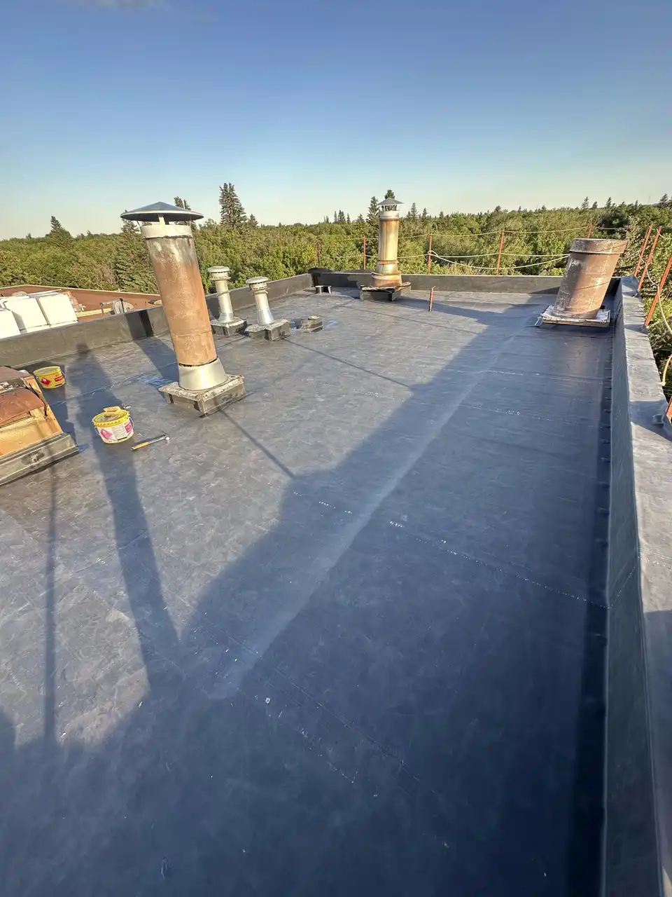 Finished EPDM rubber membrane flat roof with chimney and vent flashings in Calgary