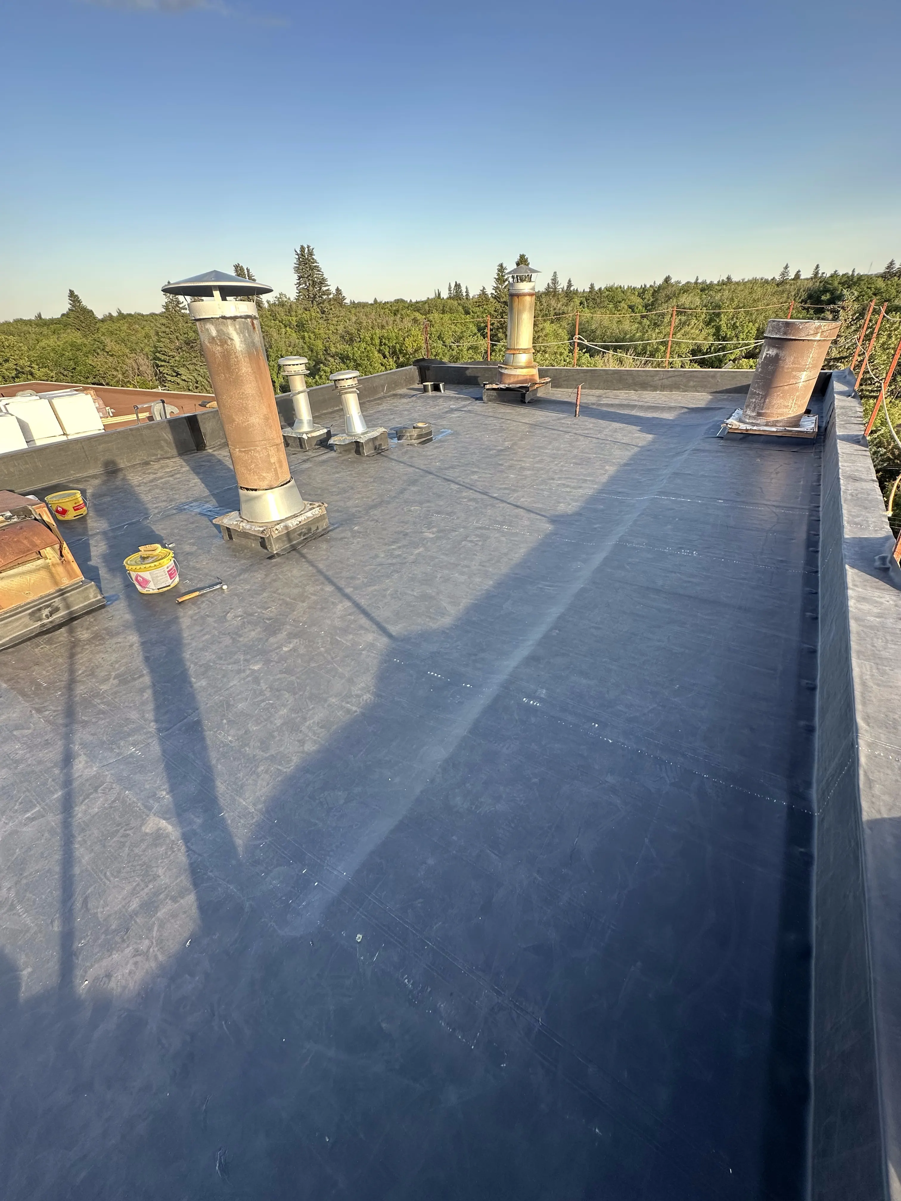 Finished EPDM rubber membrane flat roof with chimney and vent flashings in Calgary