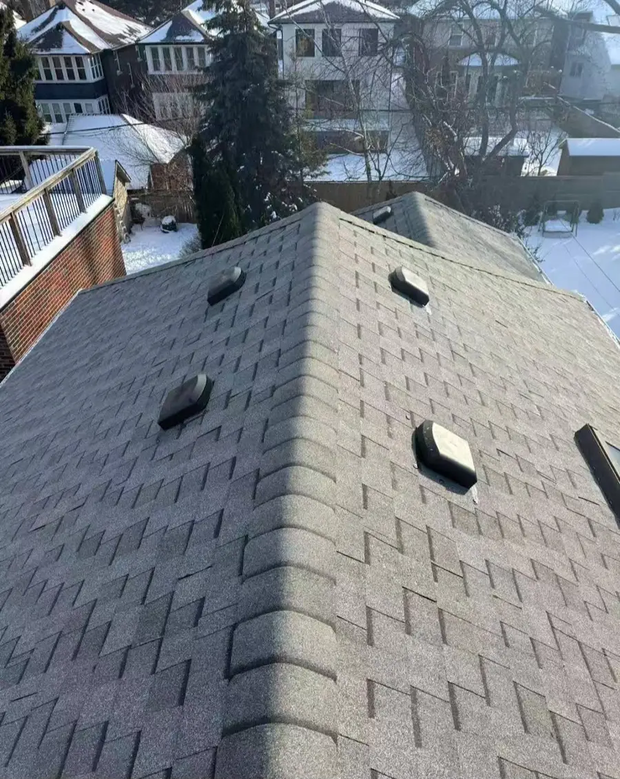 Finished grey architectural asphalt shingle roof with hip ridge caps in Calgary winter