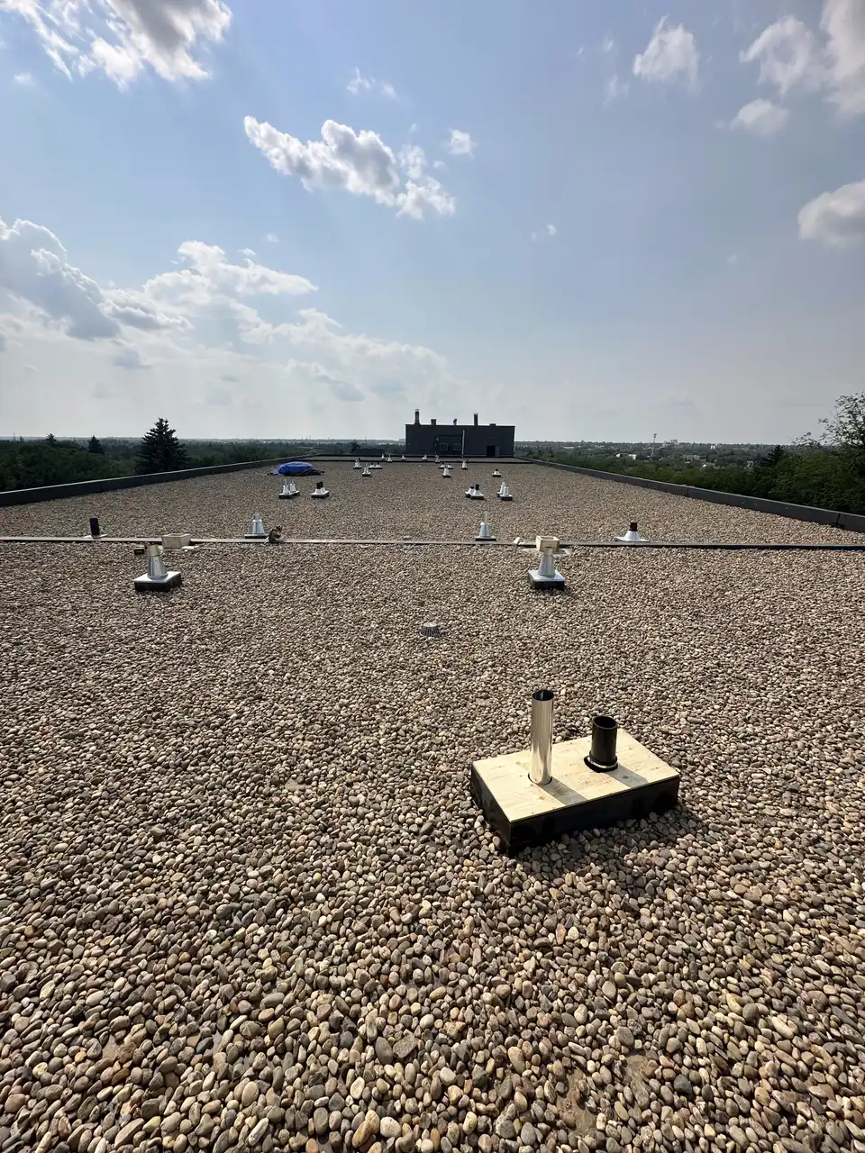 Large Calgary commercial flat roof with gravel ballast and vent stacks